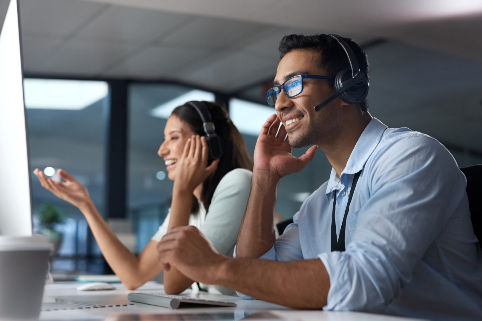 Call us anytime to get it done. Shot of a young man using a headset and computer in a modern office.