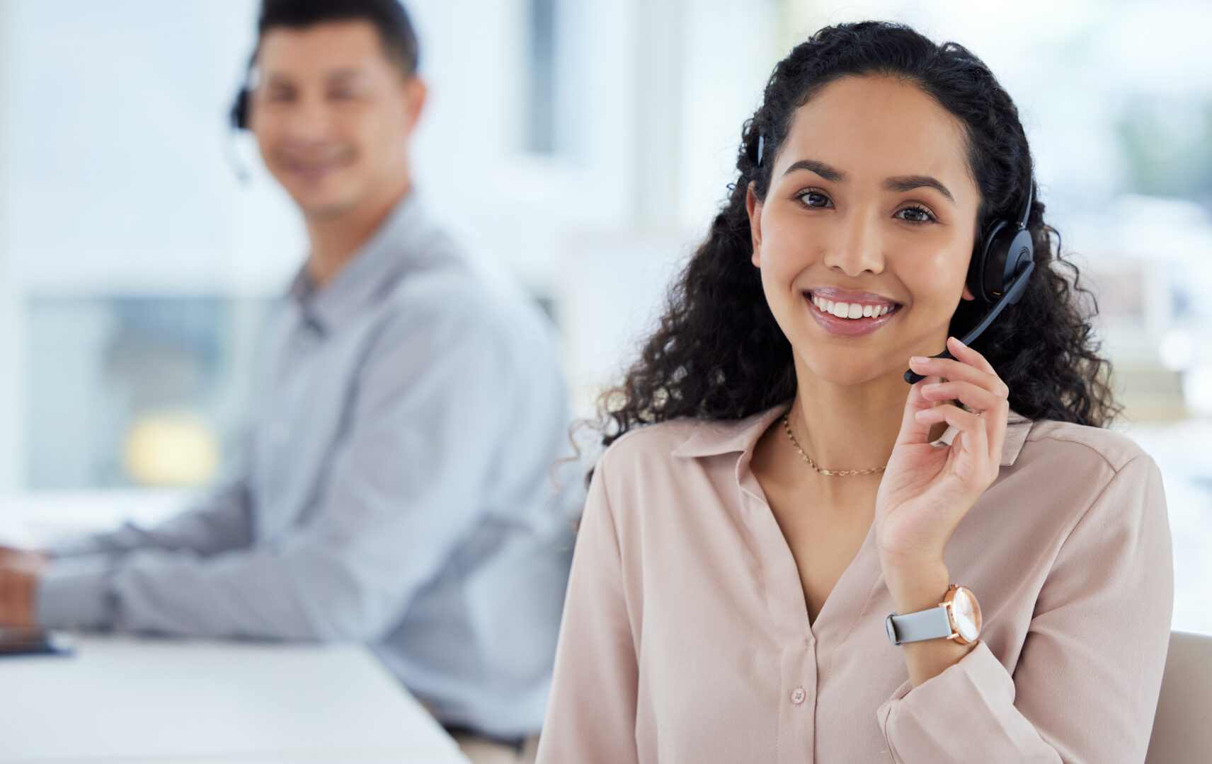 Call us and well take care of it. Portrait of a young call centre agent working in an office with her colleague in the background.